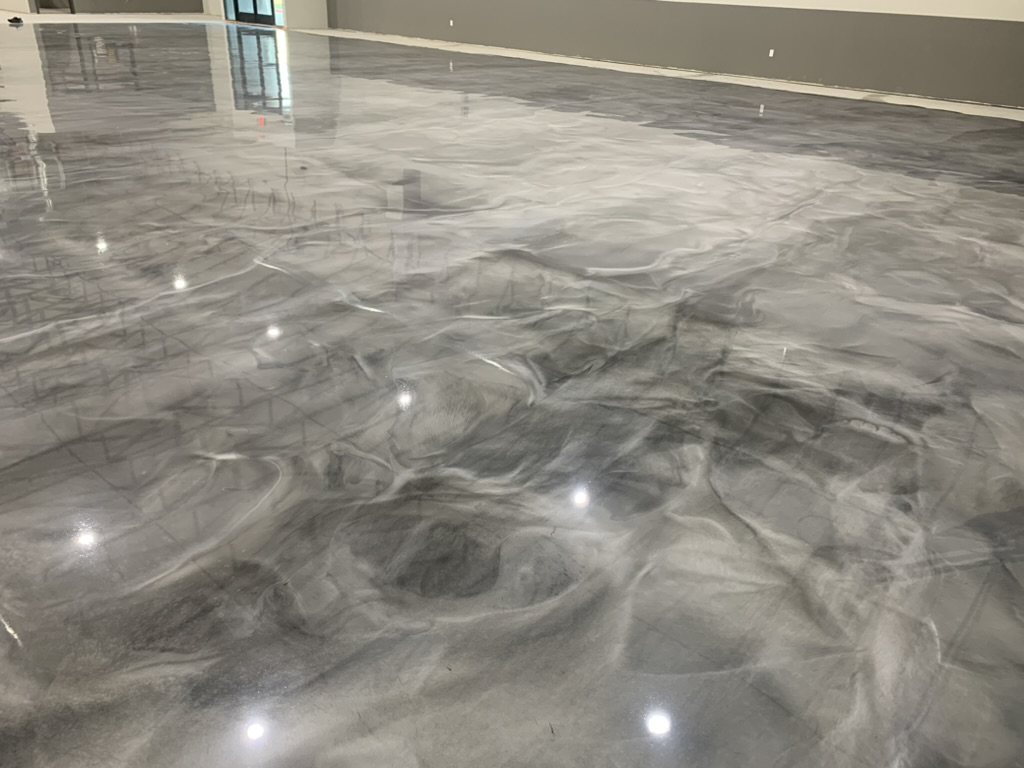 Close-up of a metallic epoxy floor showing marbled pigment movement under a high-gloss coat