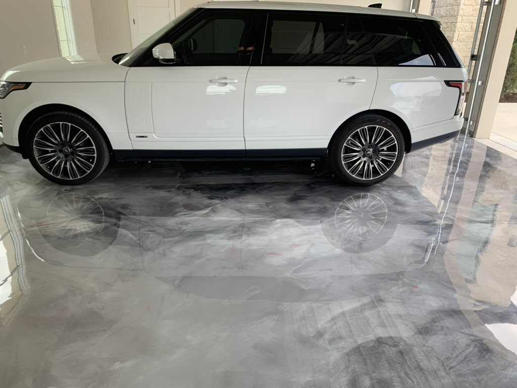 Metallic epoxy garage floor with a mirror finish reflecting a white Range Rover